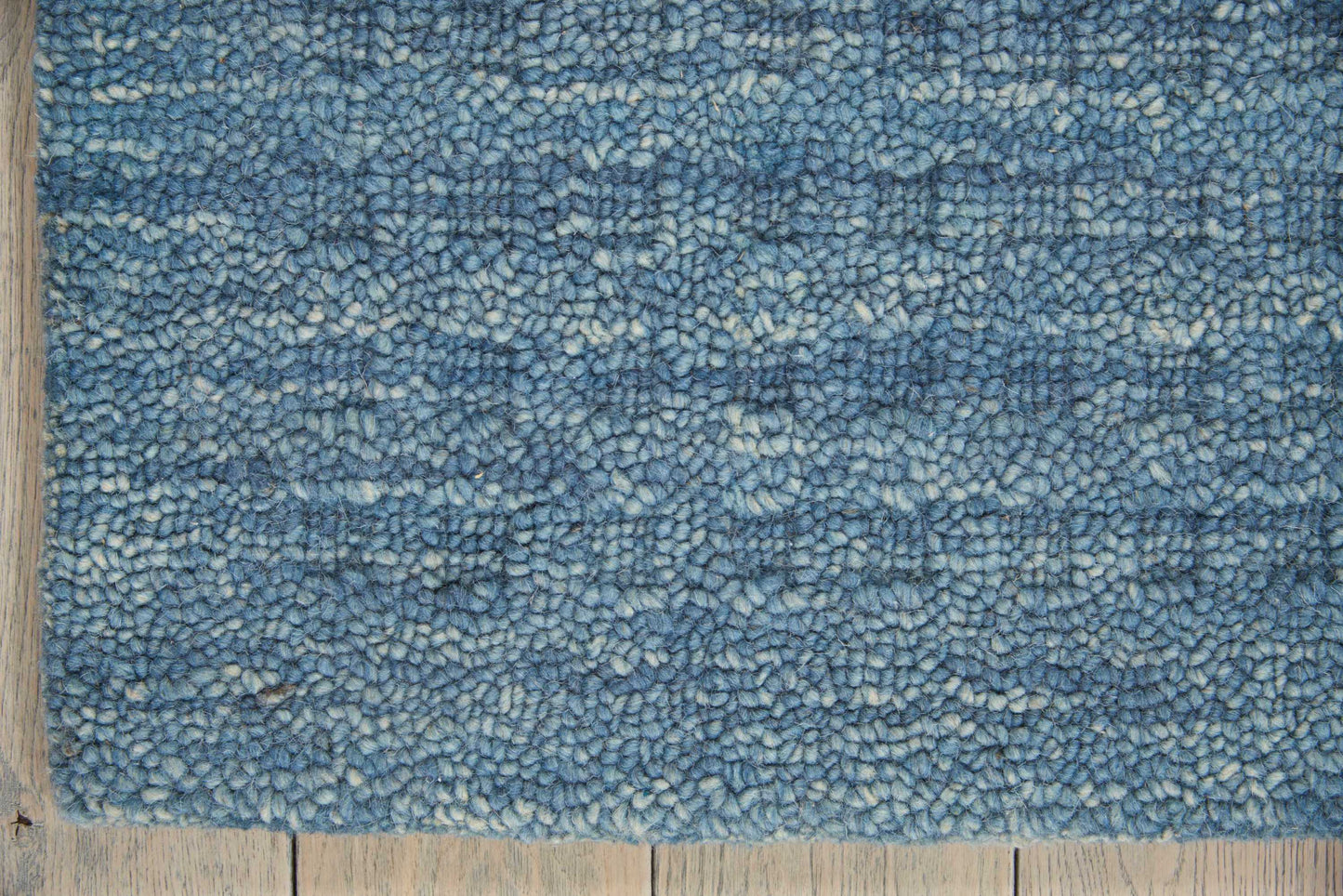 Rectangular blue shag rug with variegated light to dark blue tones and fluffy pile on wooden floor.