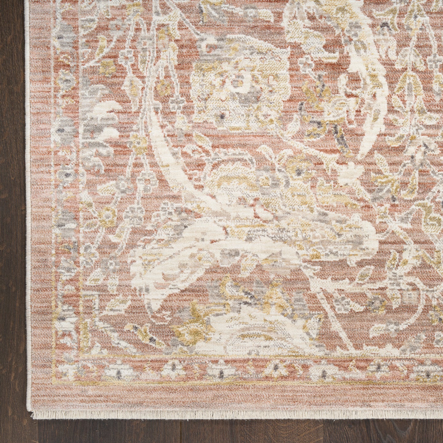 Pink oriental rug with ivory floral medallions and gold accents, woven texture, bordered edges on dark hardwood floor.
