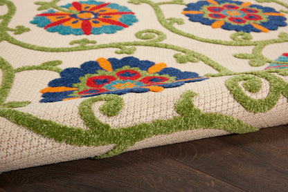 Beige woven rug with bold blue, orange, red floral motifs and green swirling vines; textured pile on dark wood.