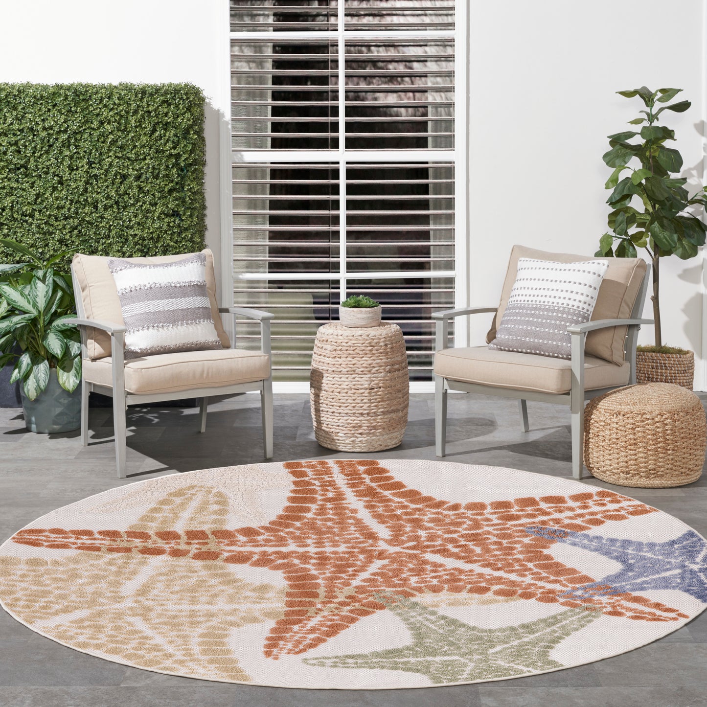 Round outdoor rug with orange starfish motif and beige, cream, blue accents; patio seating with wicker chairs.