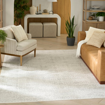 Neutral living room with beige armchair, tan leather sofa, light patterned rug, and white curved console with plants.