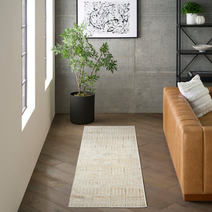 Long beige textured rug runner in a modern living room with a caramel leather sofa and a potted plant.