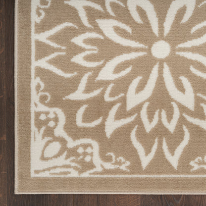 Beige area rug with white floral damask pattern and decorative border on wood floor.