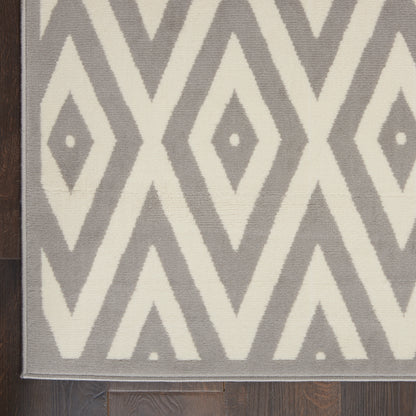 Grey and ivory geometric diamond area rug on dark wood floor; modern, bold pattern.