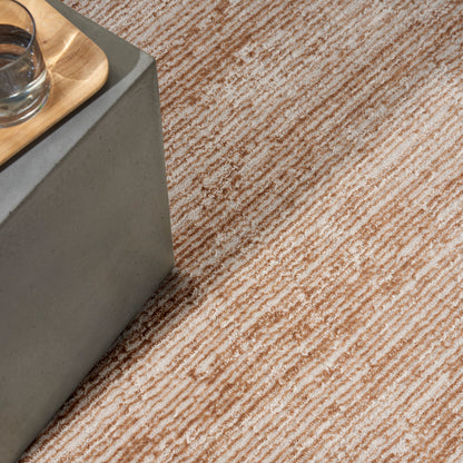 Beige-brown striped rug with textured weave under a concrete block table & wooden tray with glass.