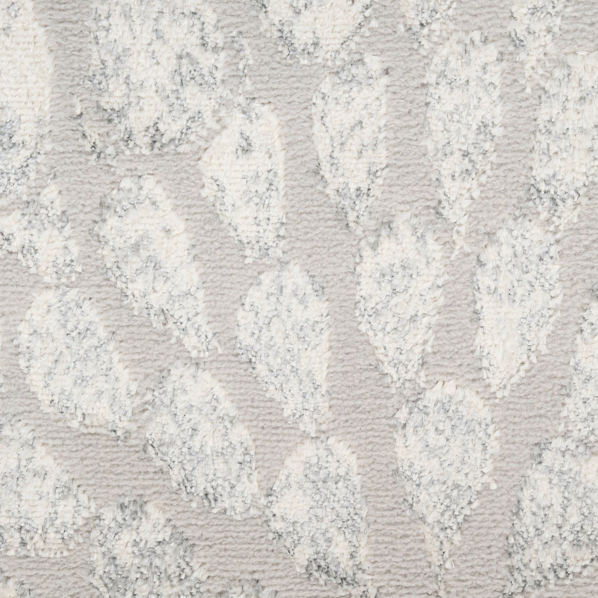 Light gray textured rug with white raised damask leaf pattern and plush pile.