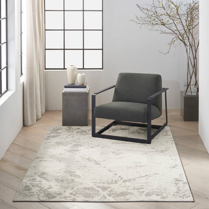 Gray cushioned lounge chair with a black metal frame on a light patterned rug in a bright minimalist living room.