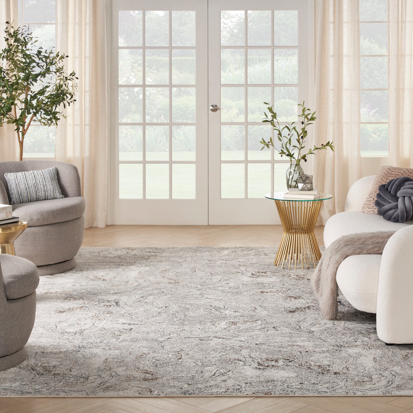 Neutral living room with French doors, light beige curtains, gray and cream furniture, and a gold wire-side table with plant.