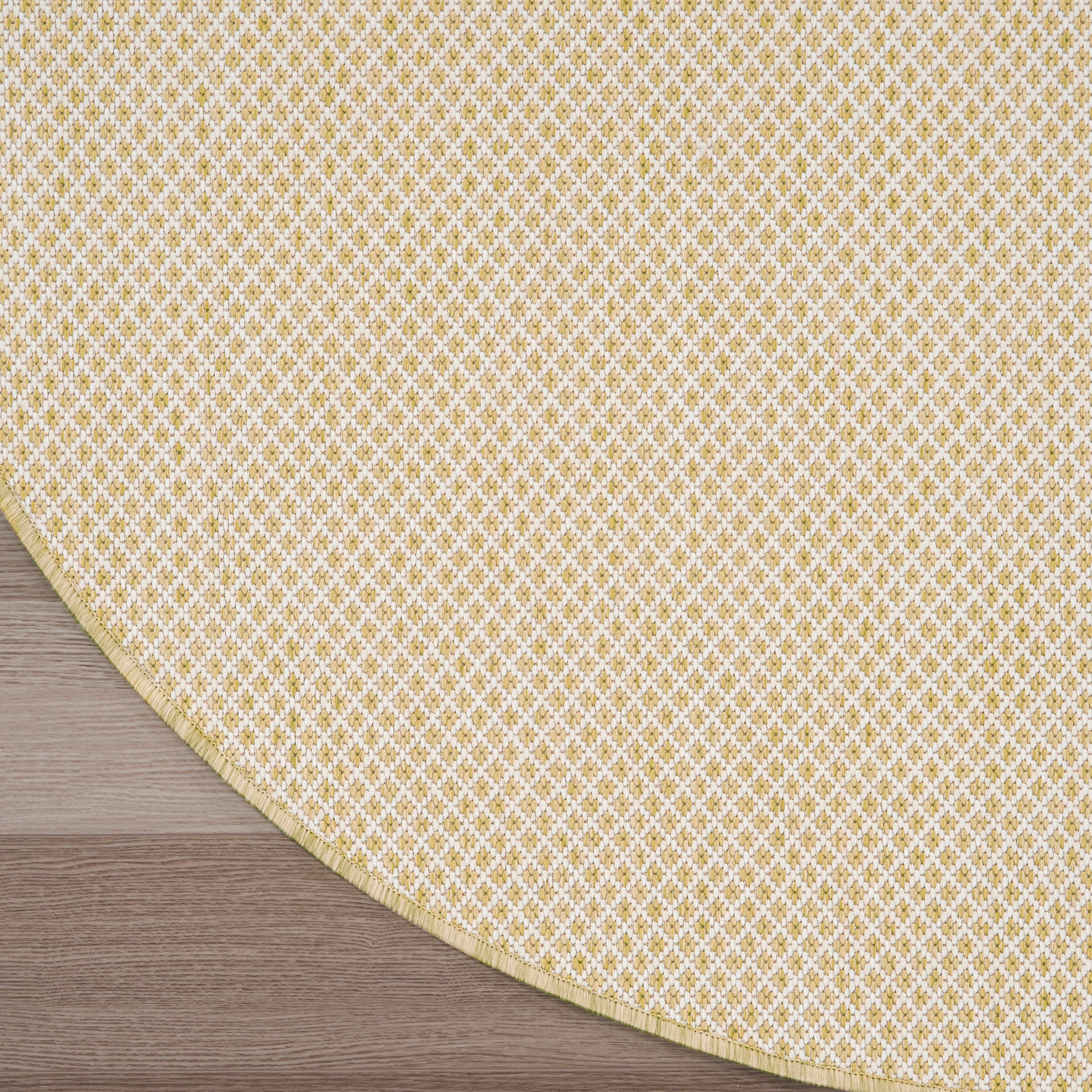Round beige modern rug on dark wood floor, featuring a beige gradient field and a curved yellow patterned edge.