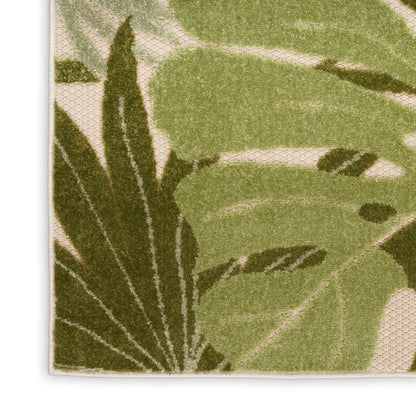 Beige outdoor rug with large dark and light green tropical leaves, tufted pile, natural botanical design.
