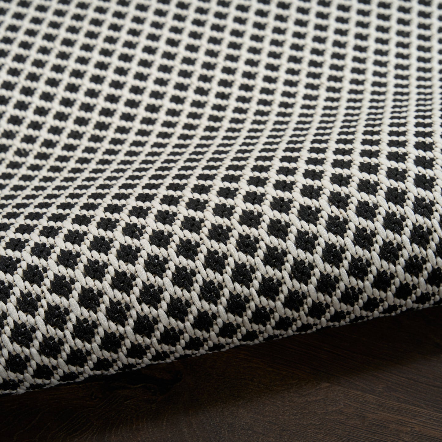 Black and white woven rug featuring a geometric lattice pattern and textured fabric for floor use.