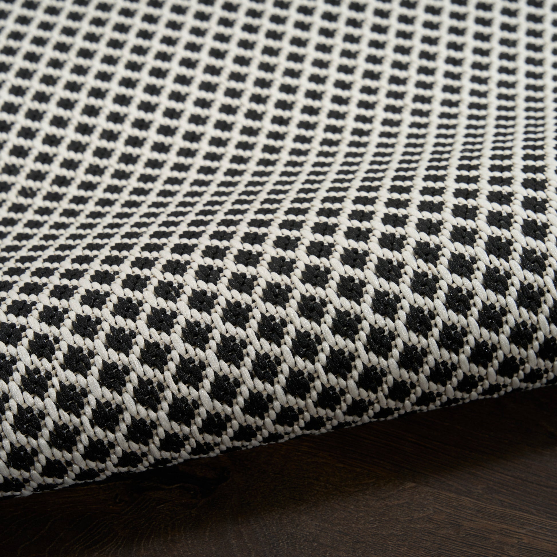 Black and white woven rug featuring a geometric lattice pattern and textured fabric for floor use.