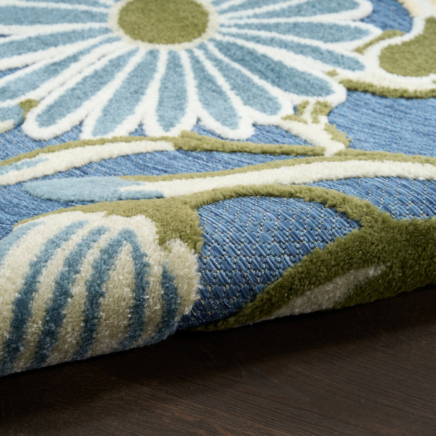 Blue floral outdoor rug with white and pale blue petals and olive-green stems; thick pile, 5' x 8'.