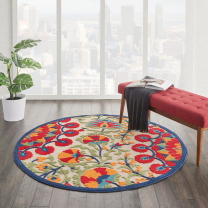 Round floral rug with red, blue, yellow and green on beige, blue border, in a bright living room with a red tufted bench.