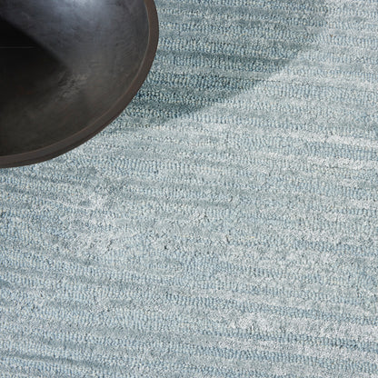 Partial view of black round pan with brown rim on a blue textured rug.
