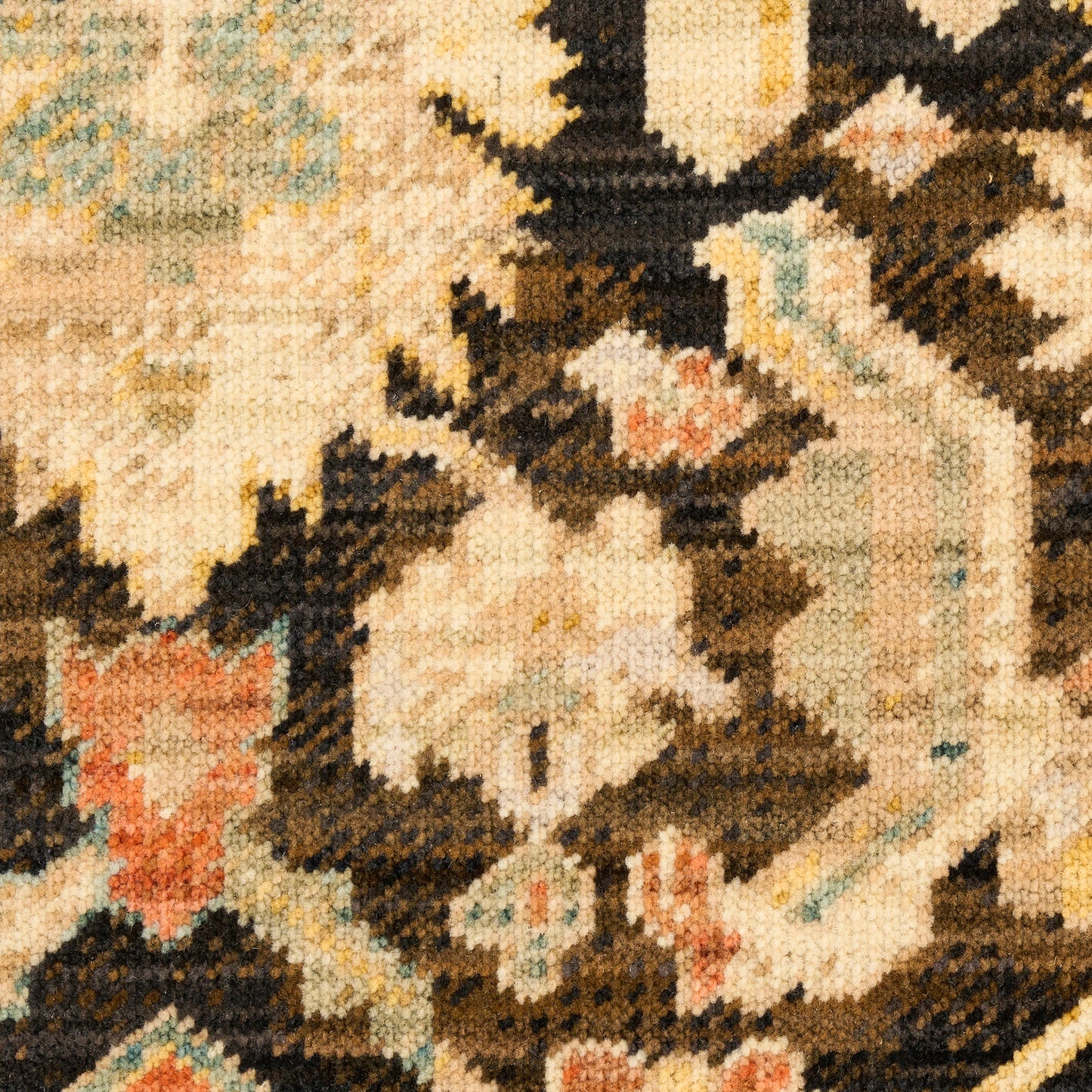 Close-up of an ornate rug with cream, beige, and brown tones, blue accents, and floral geometric patterns.