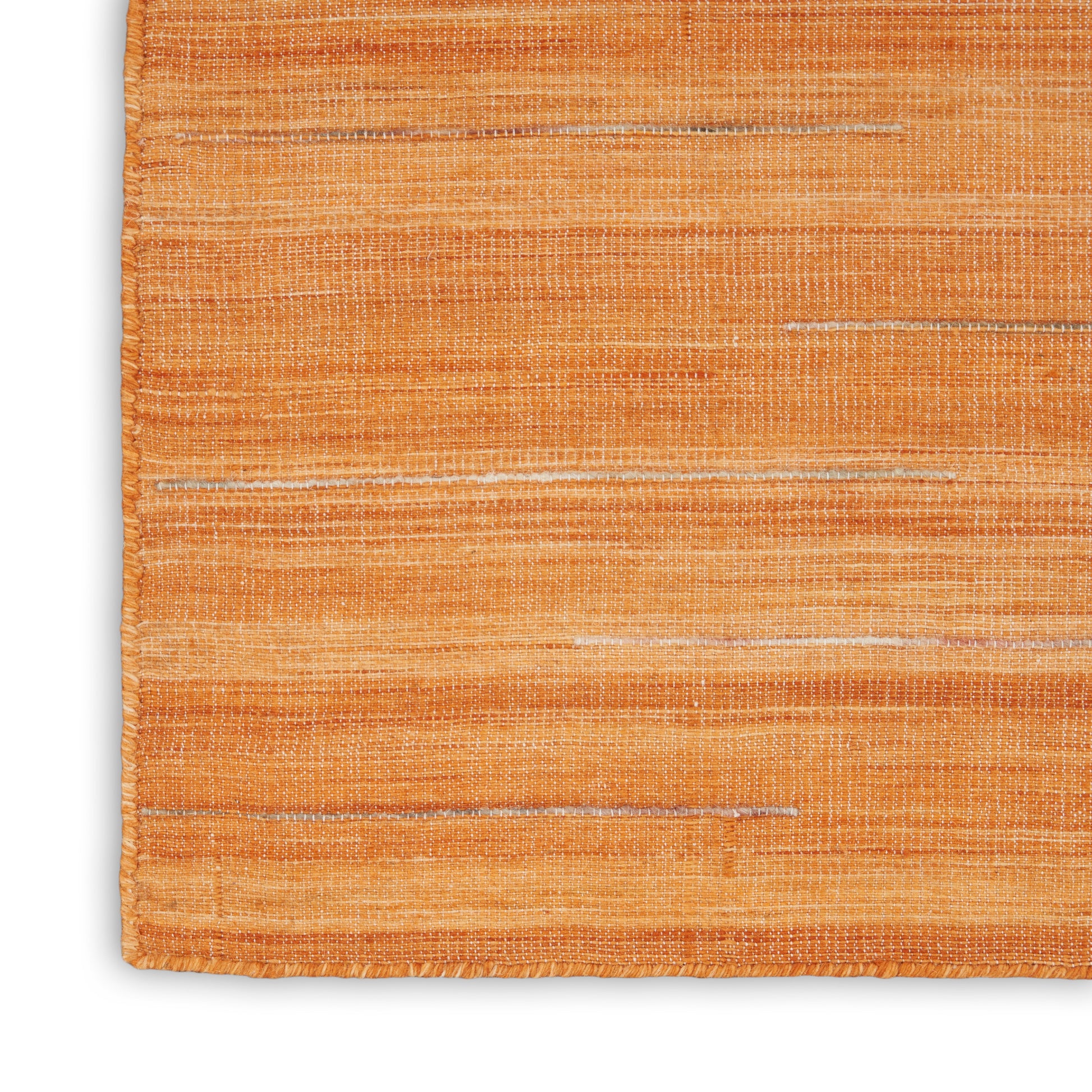 Close-up of orange woven rug with subtle horizontal stripes and textured fibers; corner visible.