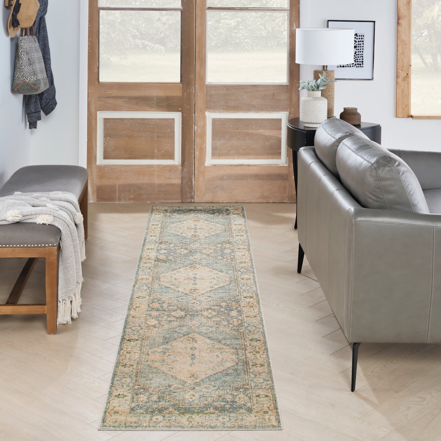 Beige and pale-blue oriental runner rug on light wood floor beside a gray sofa.