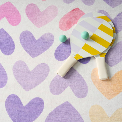 Pastel yellow-and-white diagonally striped ping-pong paddle with mint-green balls on a pastel heart-pattern fabric.