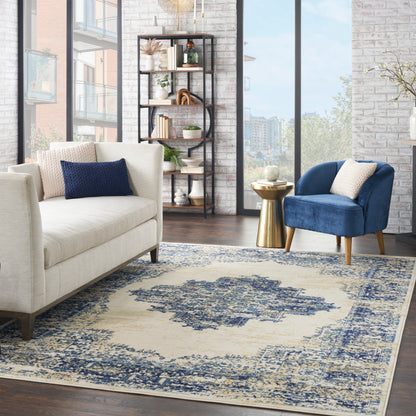 Cream sofa with navy pillow, blue velvet chair, gold side table, metal bookshelf, blue-beige rug, brick wall, tall windows.