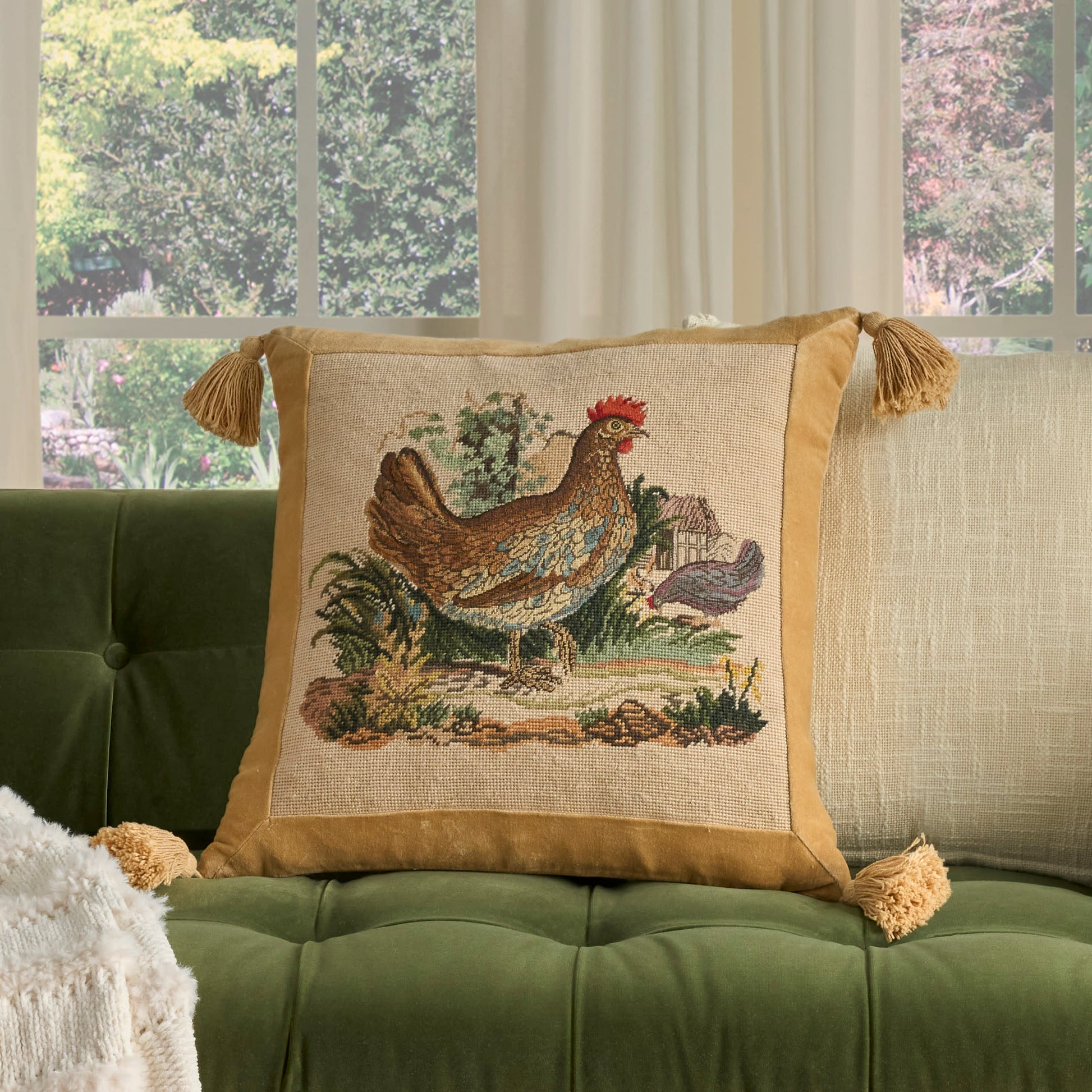 Beige 22" x 22" pillow on a tufted green sofa.