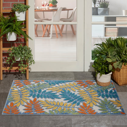 Colorful leaf-pattern outdoor doormat with blue-gray background and orange, yellow, and green leaves at a glass door threshold.