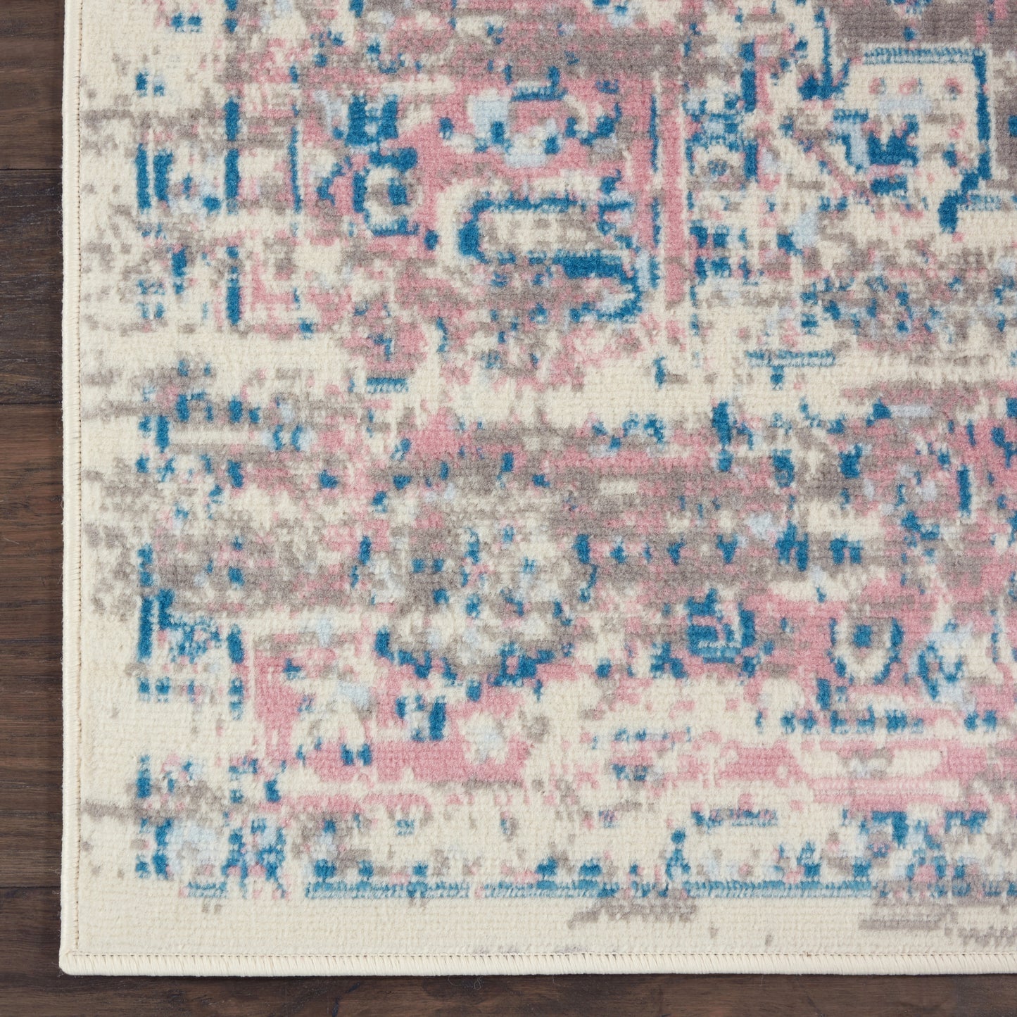 Rectangular area rug with distressed pink, blue & beige abstract pattern on ivory background; soft pile.