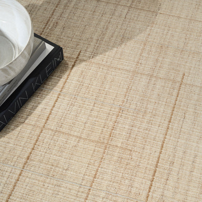 Beige textured rug with a subtle taupe plaid pattern; white ceramic bowl rests on a black hardcover book.