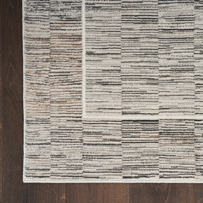 Neutral textured area rug with cream, taupe and gray rectangular blocks; modern geometric style on dark wood floor.