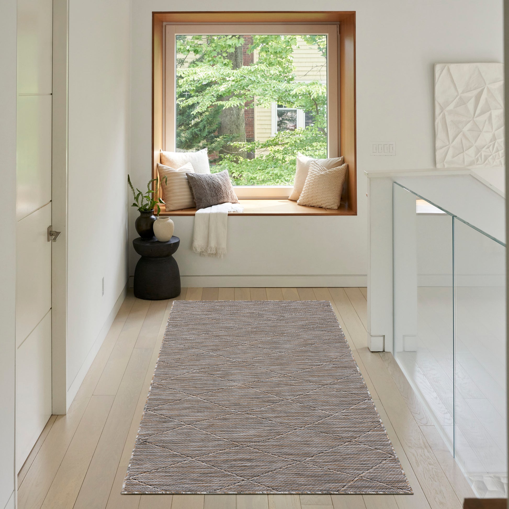 Soft gray woven runner rug with a subtle diamond pattern in a bright hallway by a window seat.