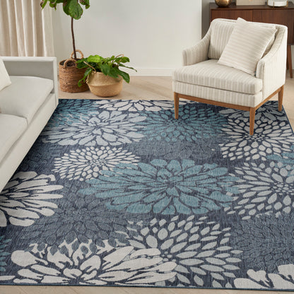 Blue and teal woven area rug with white floral motif in a cozy living room with cream sofa and beige armchair.