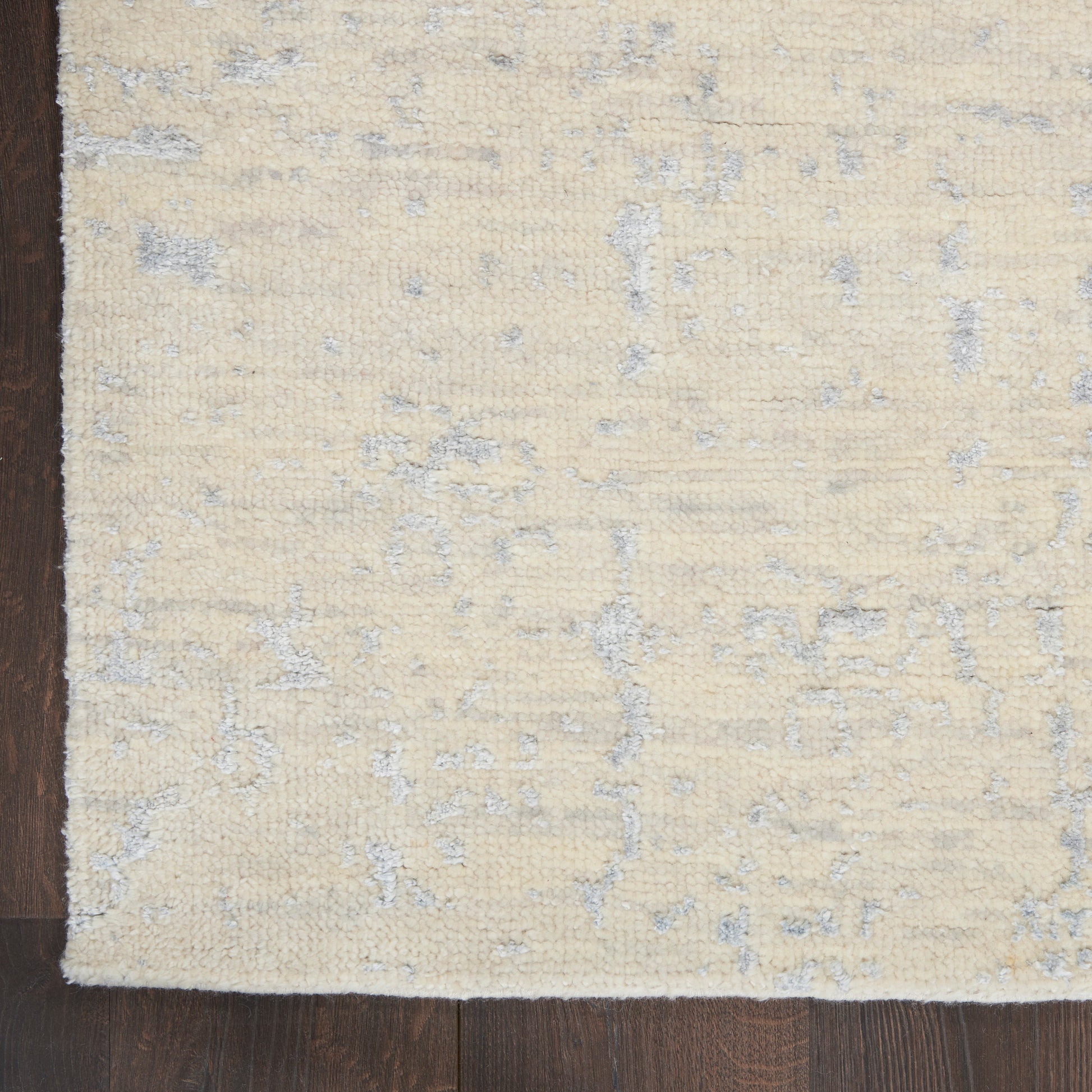 Cream beige rectangular rug with subtle blue-gray abstract pattern and soft plush pile on dark wooden floor.