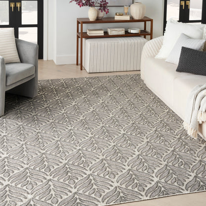 Gray and beige area rug with repeating leaf motif in a modern living room.