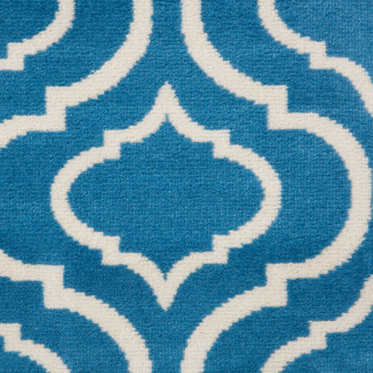 Blue rug close-up with white interlocking trellis pattern, Moroccan-inspired geometric design.