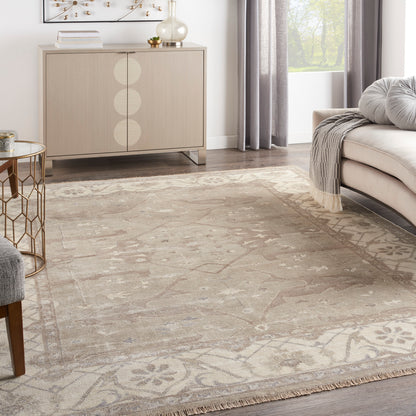 Neutral living room with rug, light wood sideboard with circles, gray sofa, glass-top gold side table, gray curtains.