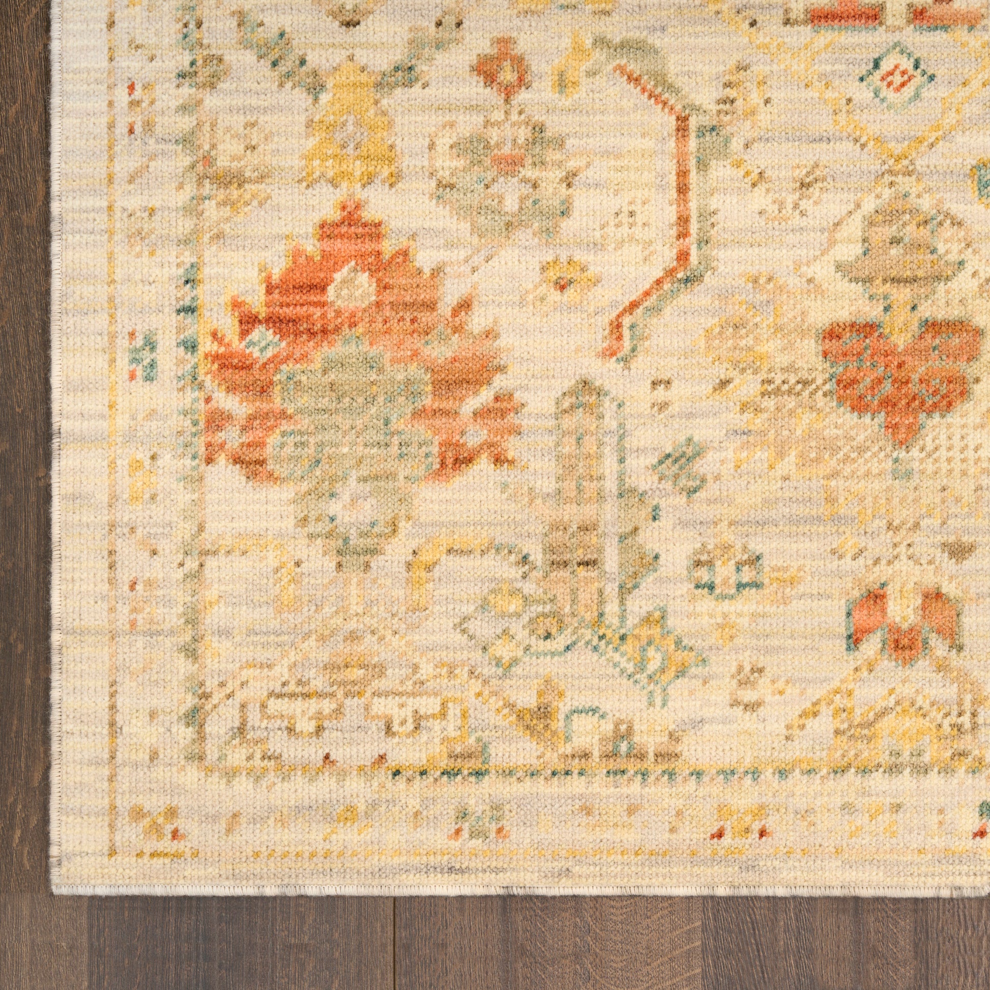 Rectangular vintage-style flatweave runner rug with cream base, rust red & teal floral medallions, amber accents on wood floor.