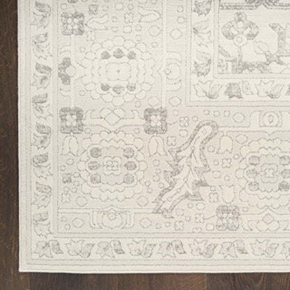 Cream area rug with ornate floral medallions and border on dark wood floor.
