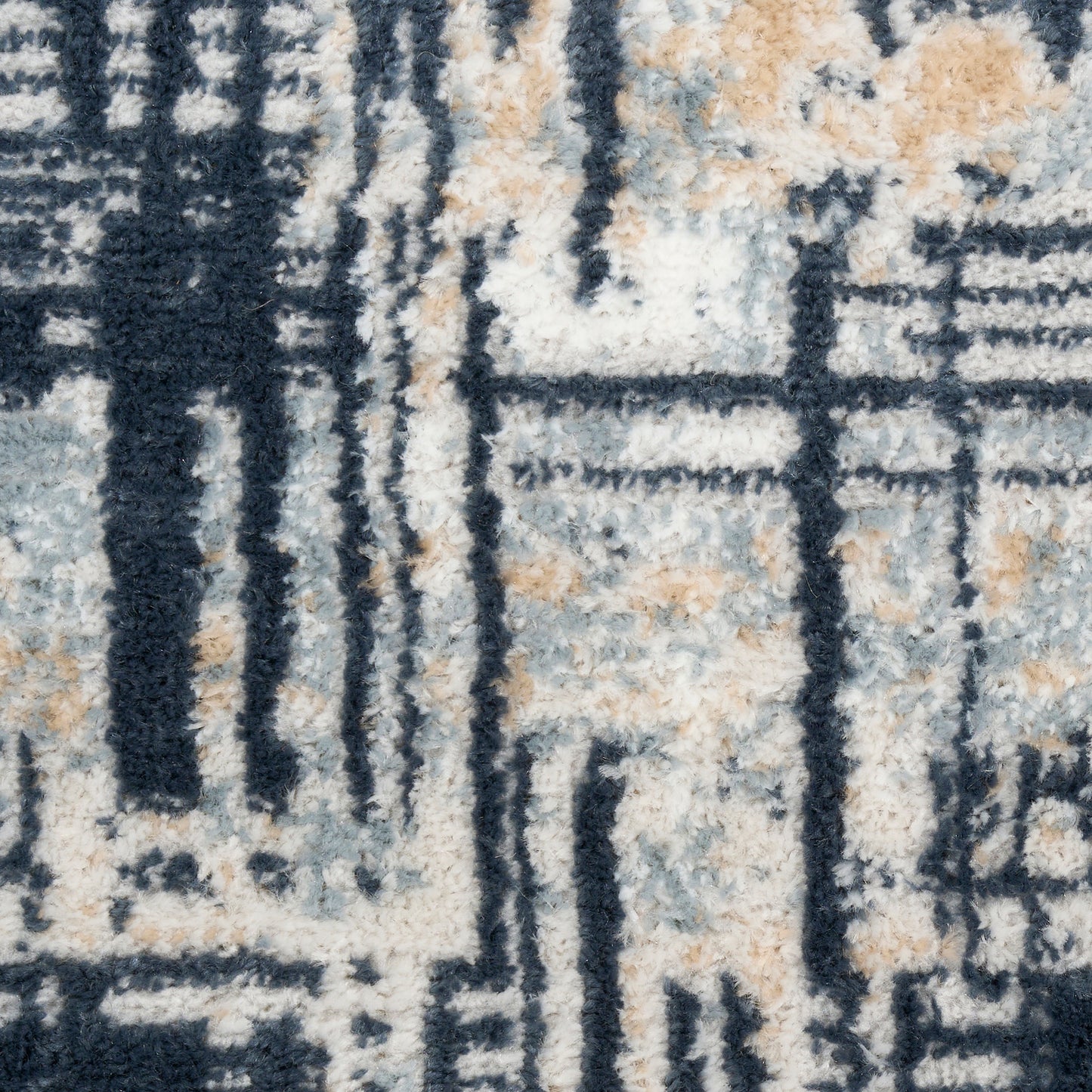 Close-up of a modern shaggy rug in navy, beige, ivory and gray with bold geometric lines.