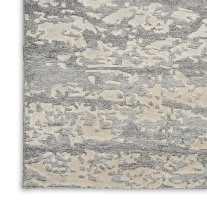Gray and beige abstract area rug with mottled blotches and soft, textured pile.