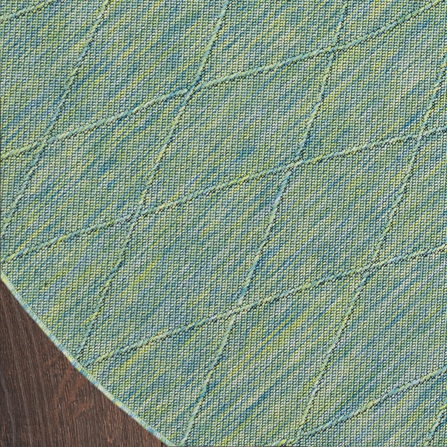 Round teal-blue denim-style rug with lime-green diagonal diamond quilting on wooden floor