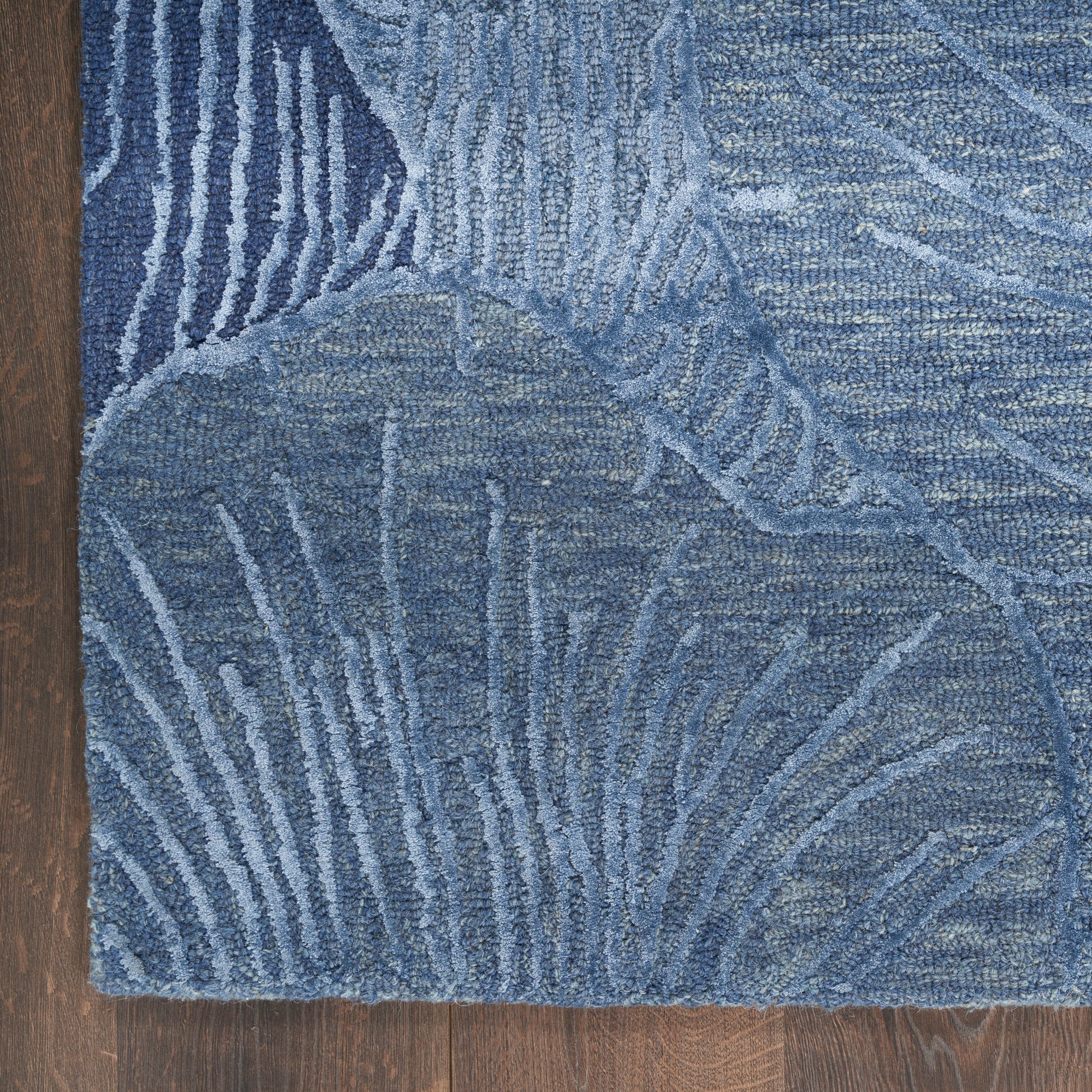 Blue abstract-pattern area rug with palm-leaf motifs and varying blue tones on a wooden floor.
