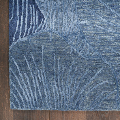 Blue abstract-pattern area rug with palm-leaf motifs and varying blue tones on a wooden floor.