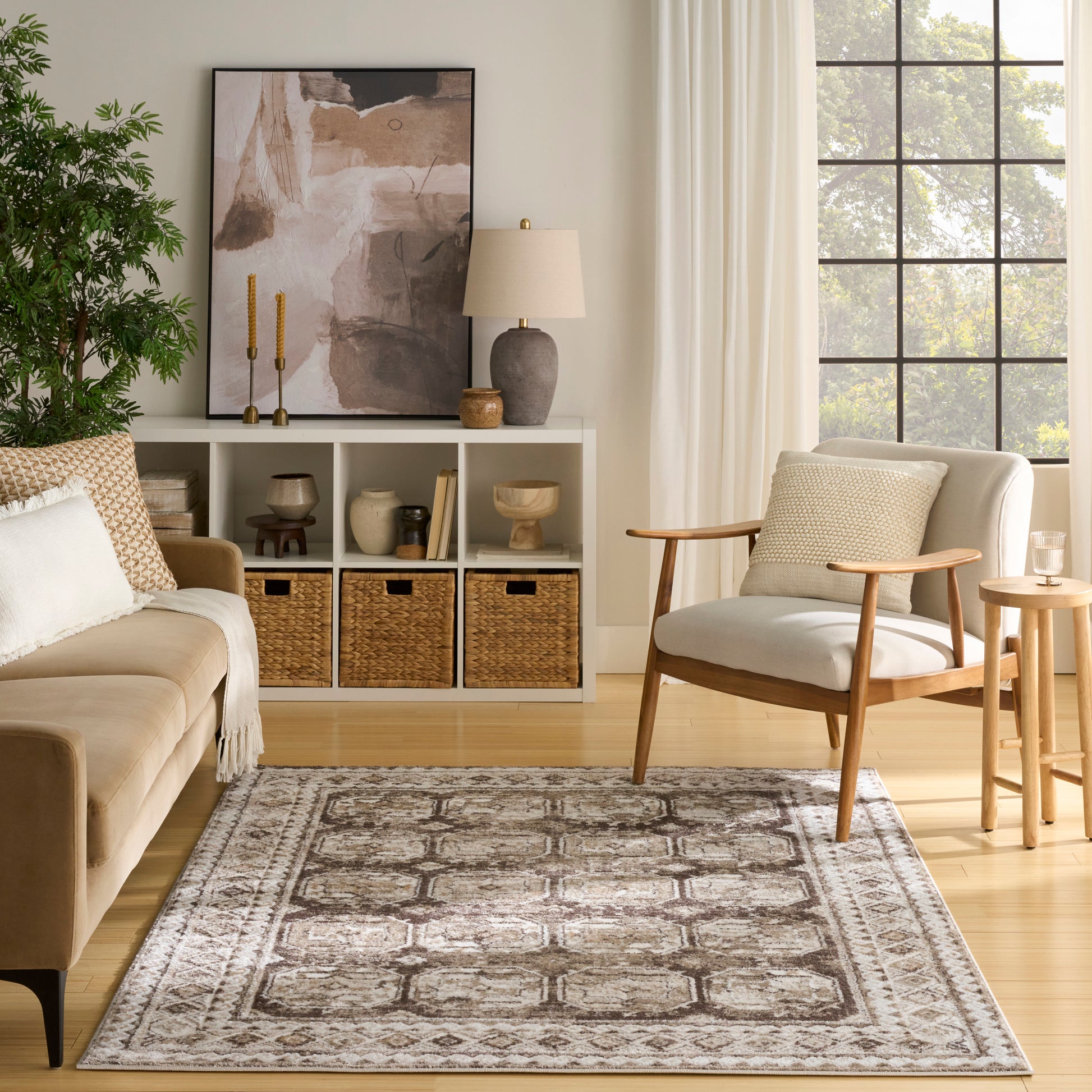 Neutral gray-beige geometric area rug with distressed pattern, paired with mid-century chair and cozy living room decor.