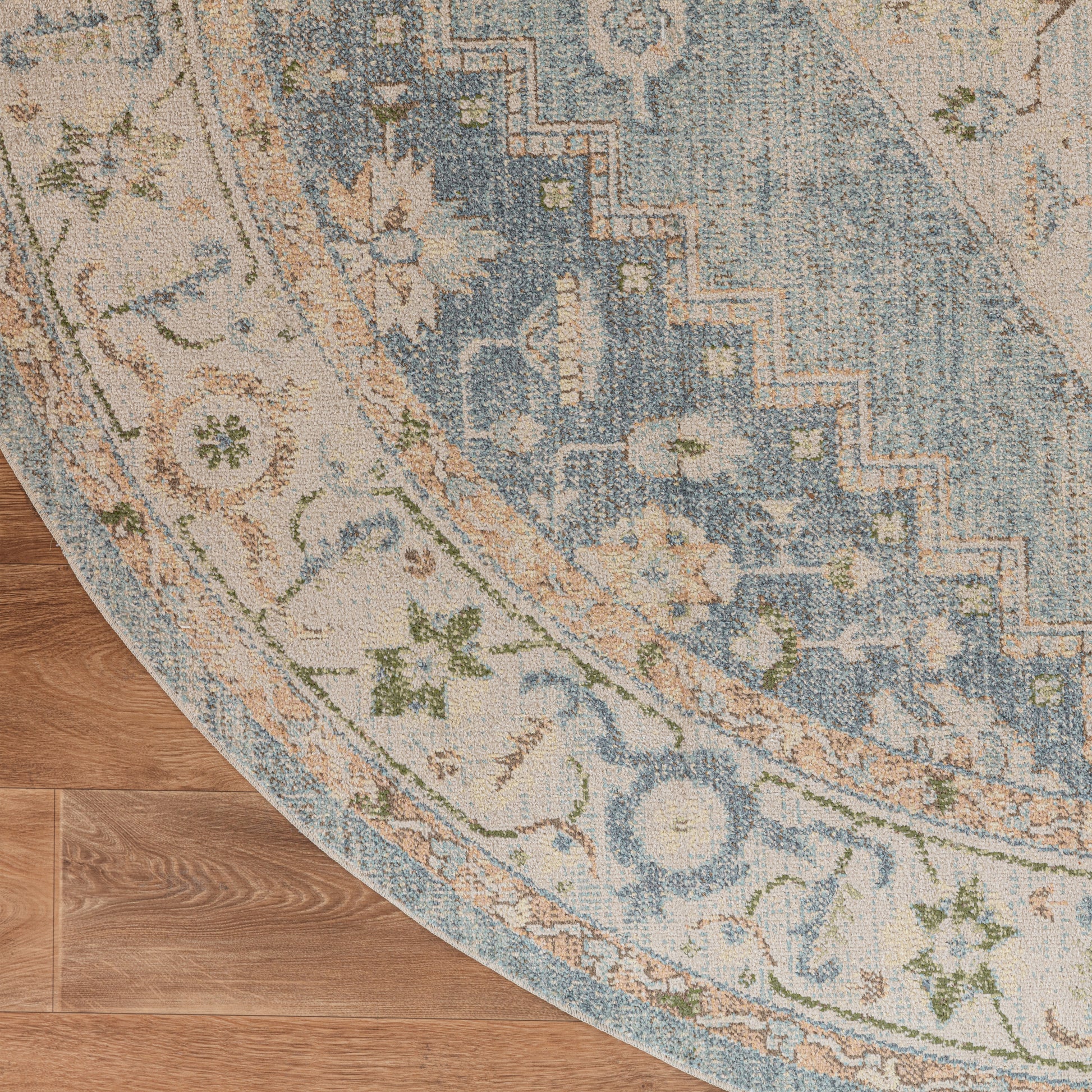 Round oriental-style rug with blue and ivory floral pattern on warm wood floor.
