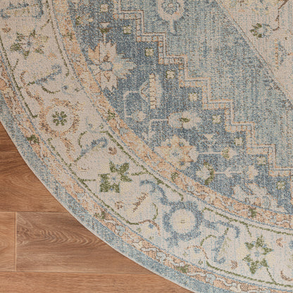 Round oriental-style rug with blue and ivory floral pattern on warm wood floor.
