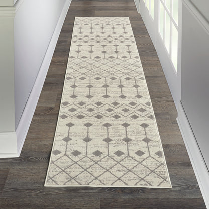 Cream hallway runner rug with a light gray geometric diamond and trellis pattern on a dark wood floor.