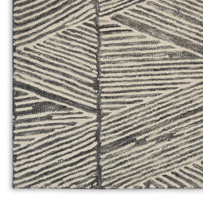 Beige textured rug close-up with dark gray palm-leaf pattern; loop pile, modern geometric style.