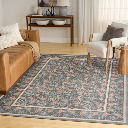 Blue floral area rug with a pale border in a bright living room, paired with a tan leather sofa and beige armchair.