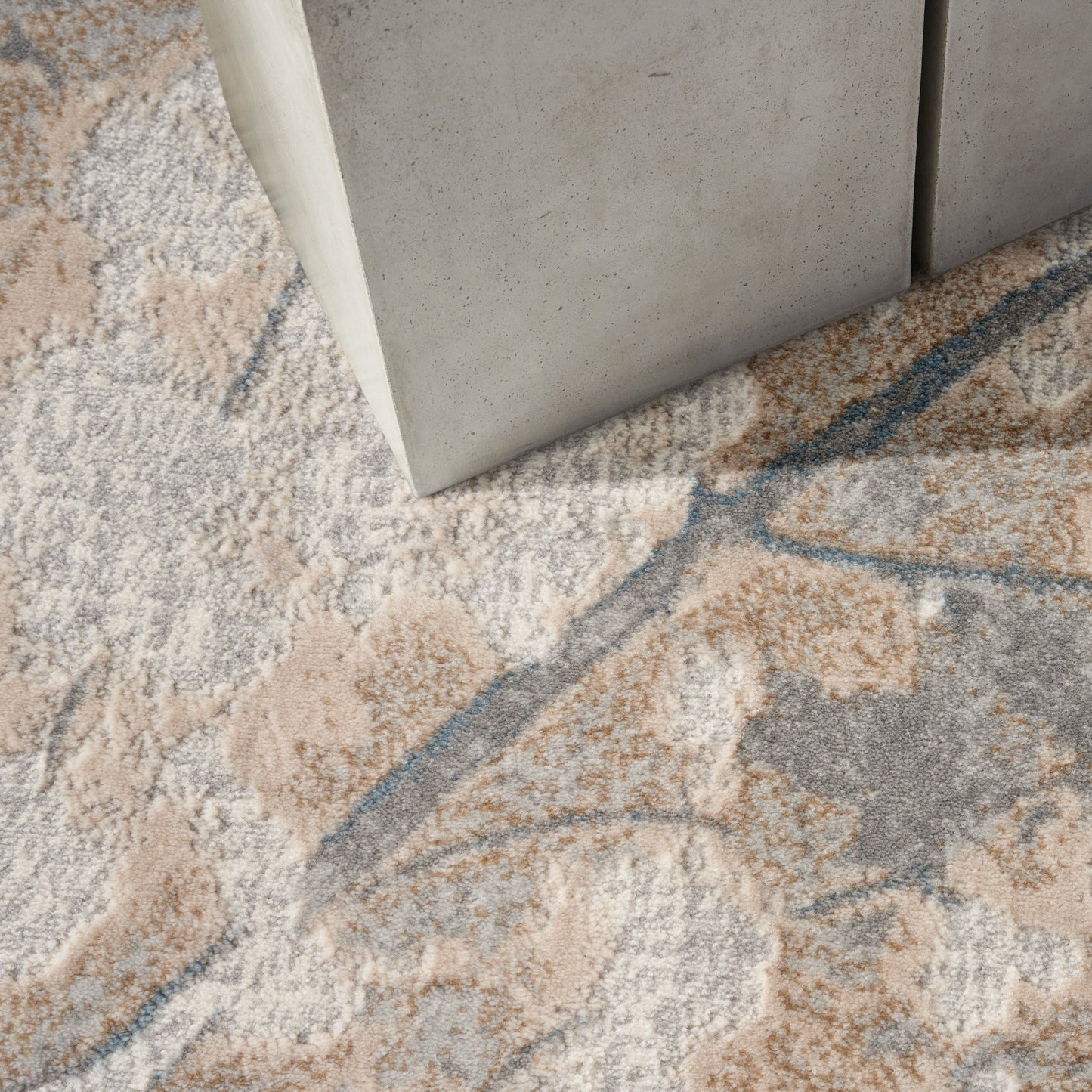 Rectangular area rug with a soft pile in beige, gray, peach and blue abstract floral pattern.