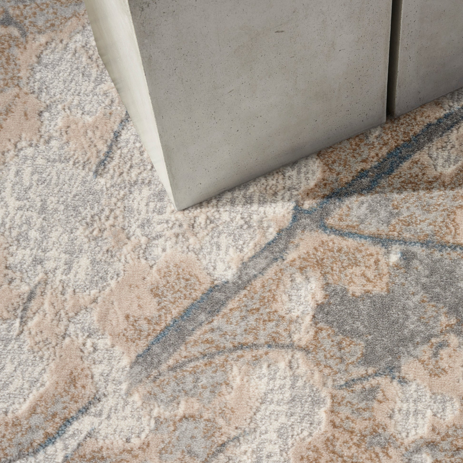 Rectangular area rug with a soft pile in beige, gray, peach and blue abstract floral pattern.